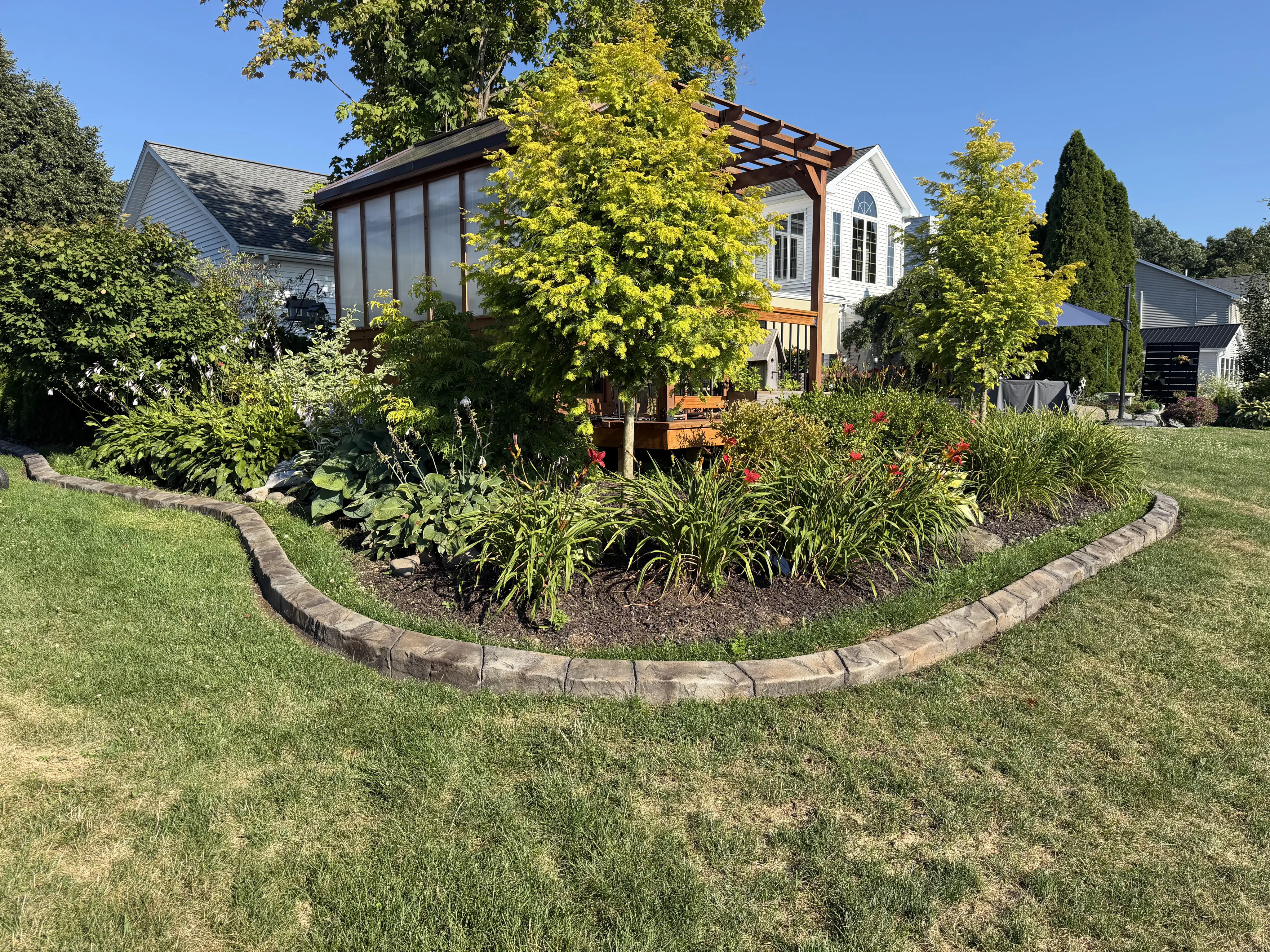 Landscaped backyard with decorative concrete curbing around a garden bed
